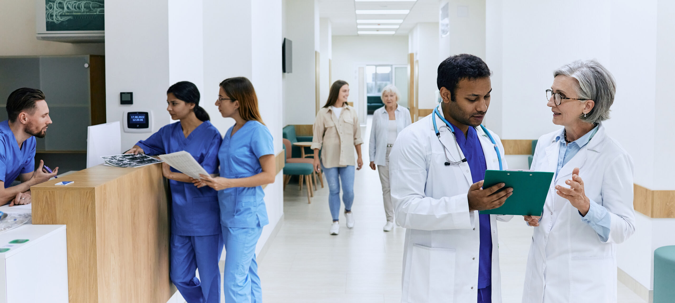 Panoramic view of clinic corridor while workflow of hospital with doctors, patients and medical staff. Day hospital