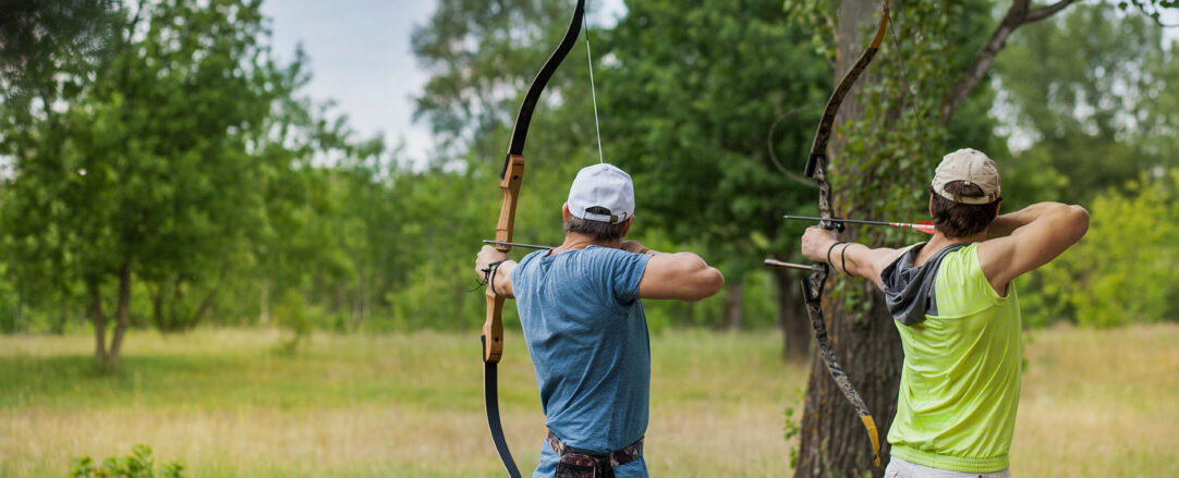 Two men compete in archery on vacation in the forest